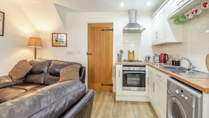 A compact kitchen with a washing machine, a stove, and a sink.