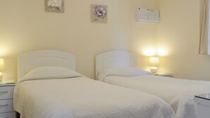 A twin room with two beds, bedside tables, and wall-mounted air conditioning units. - 2 bedroom accommodation in Scarning, near Dereham (Scarning, near Dereham)