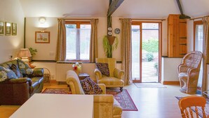 A cozy living room with a sofa, armchairs, a dining table, and a large window.