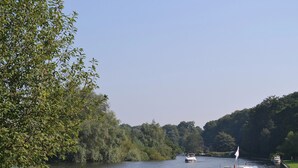 A river with boats, a grassy bank, and trees in the background.