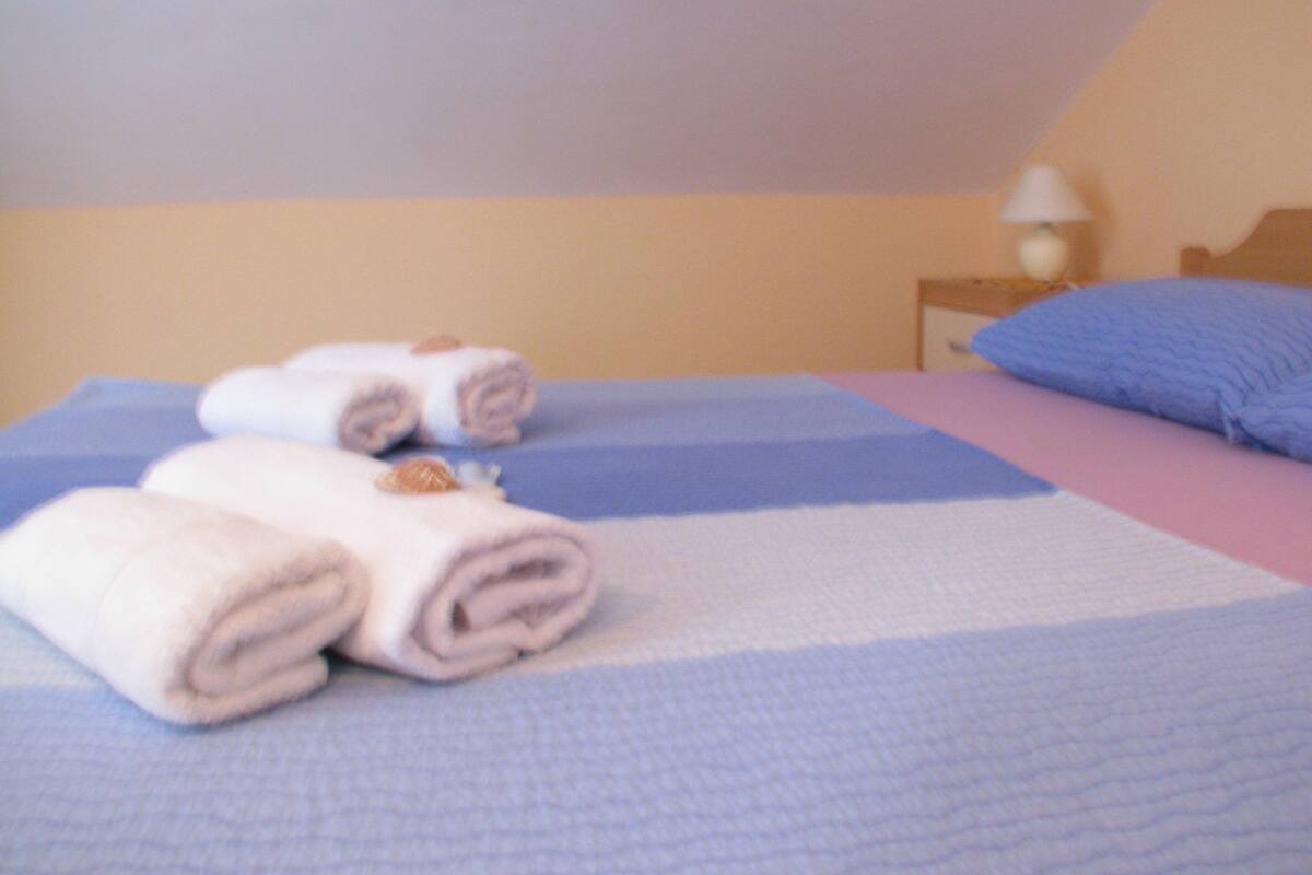 A bed with rolled towels and a blue and white striped bedspread.