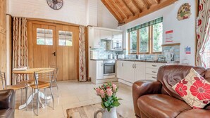 Un interior acogedor con techo de madera, una zona de comedor con sillas, una cocina con armarios y una sala de estar con sofá.