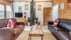 Una sala de estar acogedora con sofás de cuero, una mesa de centro de madera, un televisor y una chimenea.
