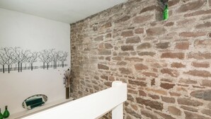 A room with a stone wall, a white railing, and a wall-mounted decoration of bare trees. - 3 bedroom accommodation in Gosforth, near Wast Water (Gosforth, near Wast Water)