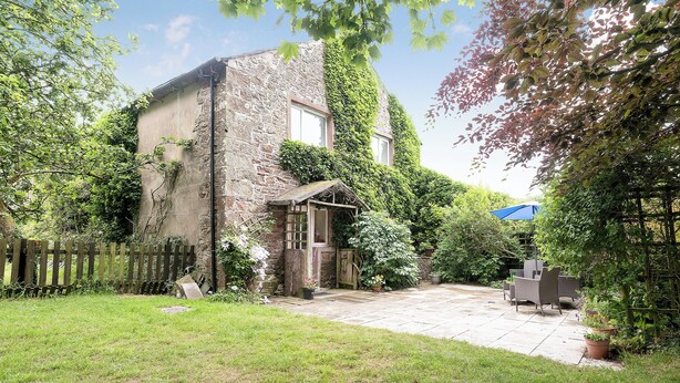 A stone building with ivy, a wooden fence, and a patio with outdoor furniture. - 3 bedroom accommodation in Gosforth, near Wast Water (Gosforth, near Wast Water)