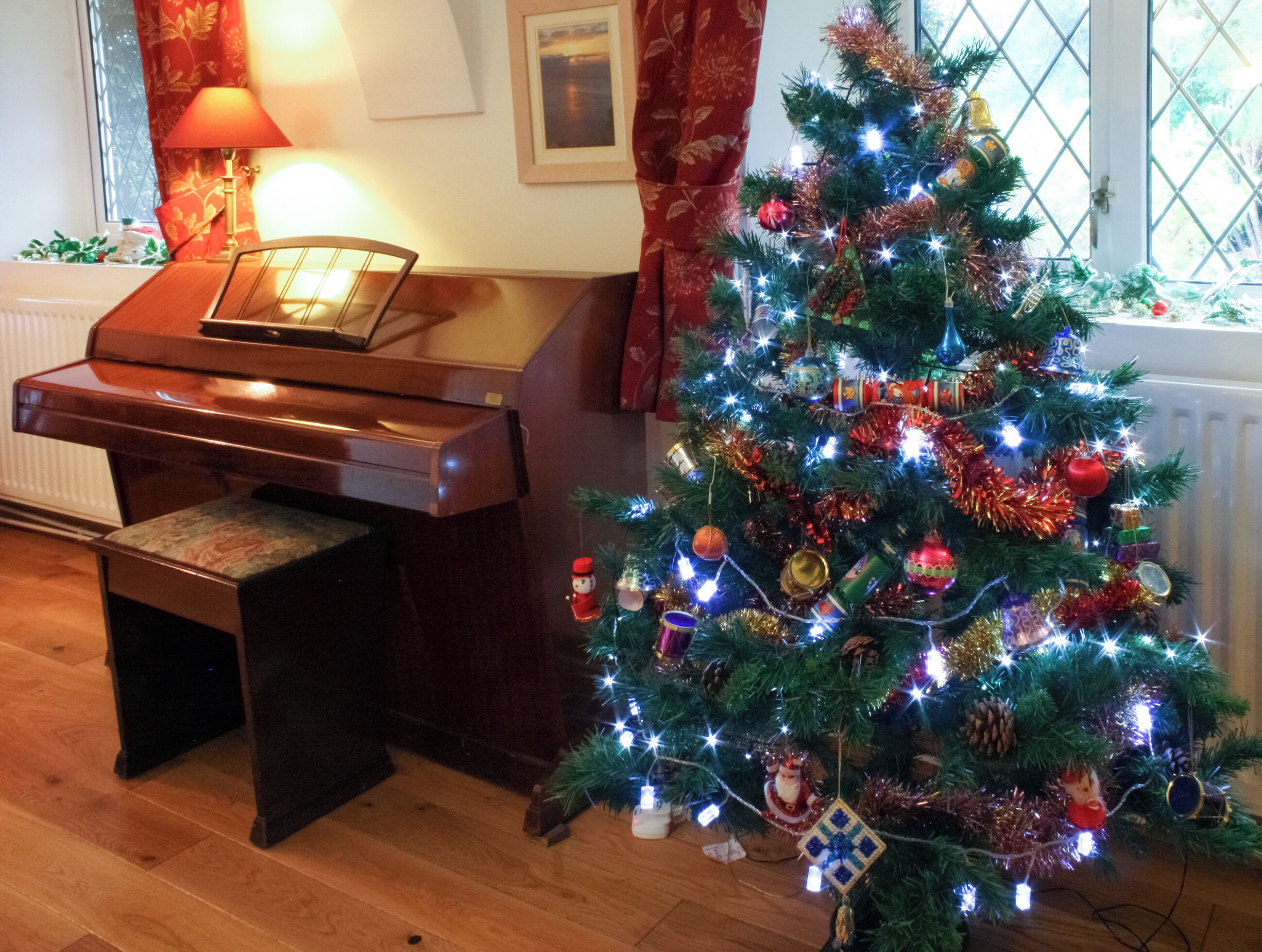 A piano in a room with a decorated Christmas tree.