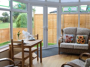 A conservatory with a dining table, chairs, and a cushioned seating area with patterned cushions. - 1 bedroom accommodation in Ryal, near Corbridge (Ryal, near Corbridge)