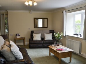 Una sala de estar con un sofá, una mesa de centro, un espejo y una ventana con cortinas.