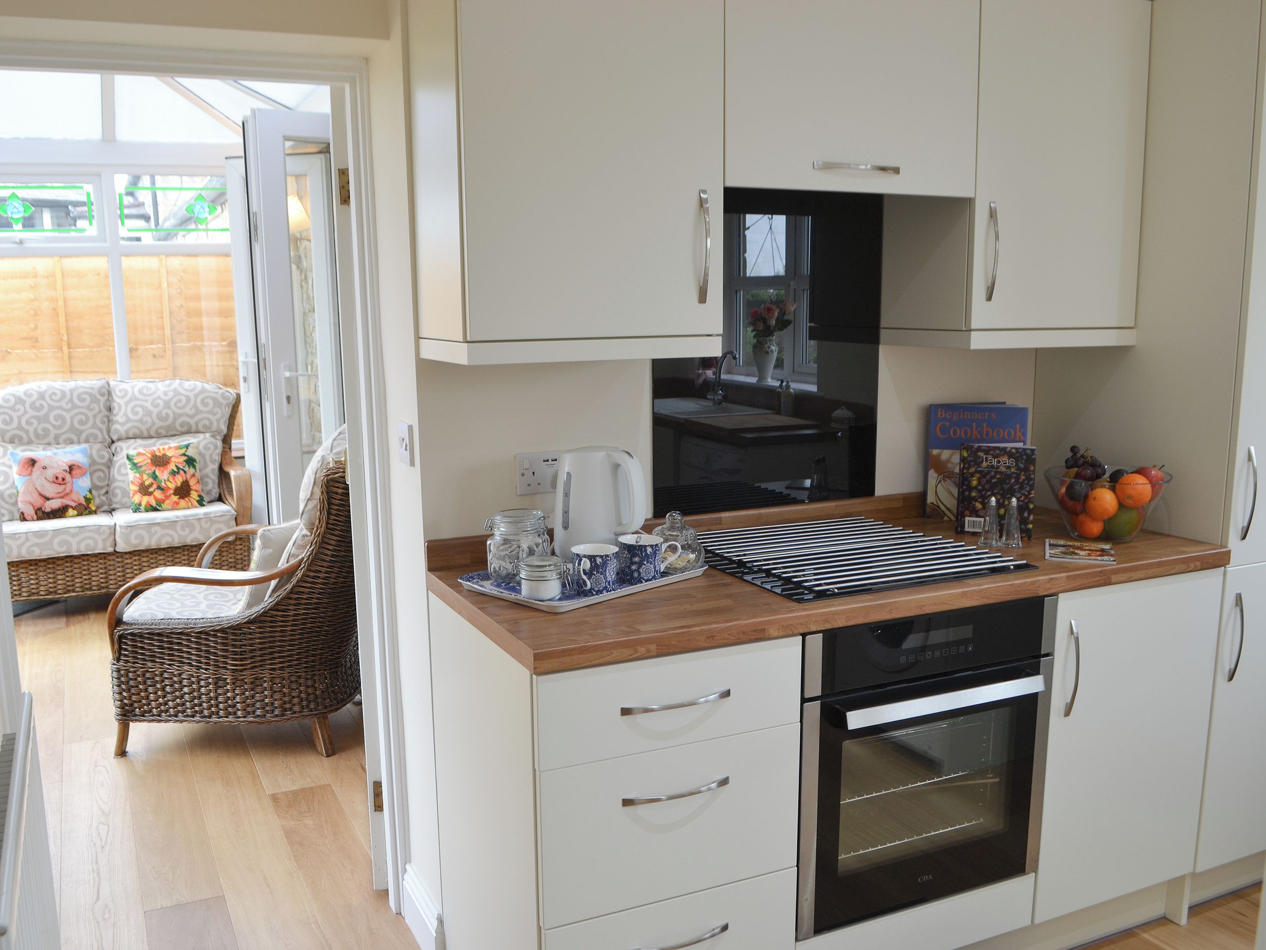 A kitchen with white cabinets, a coffee maker, a kettle, and a fruit bowl.