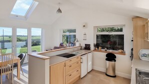 Une cuisine moderne dotée d’un îlot central, de grandes fenêtres et offrant une vue sur l’extérieur.