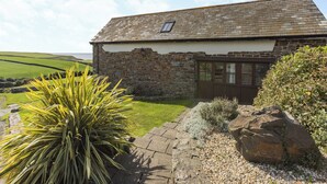 A stone building with a sloped roof, a small window, and a sign that reads 'Smugglers Retreat.'