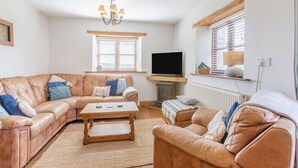 A living room with a brown leather sofa, a wooden coffee table, a television, and a fireplace.