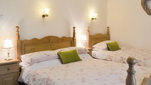 A bedroom with two wooden beds, each with a headboard, bedside lamps, and floral bedding.