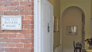 A brick wall with a sign reading "THE OLD BUTLER'S HOUSE". - The Old Butler's House (Cley-next-the-Sea)