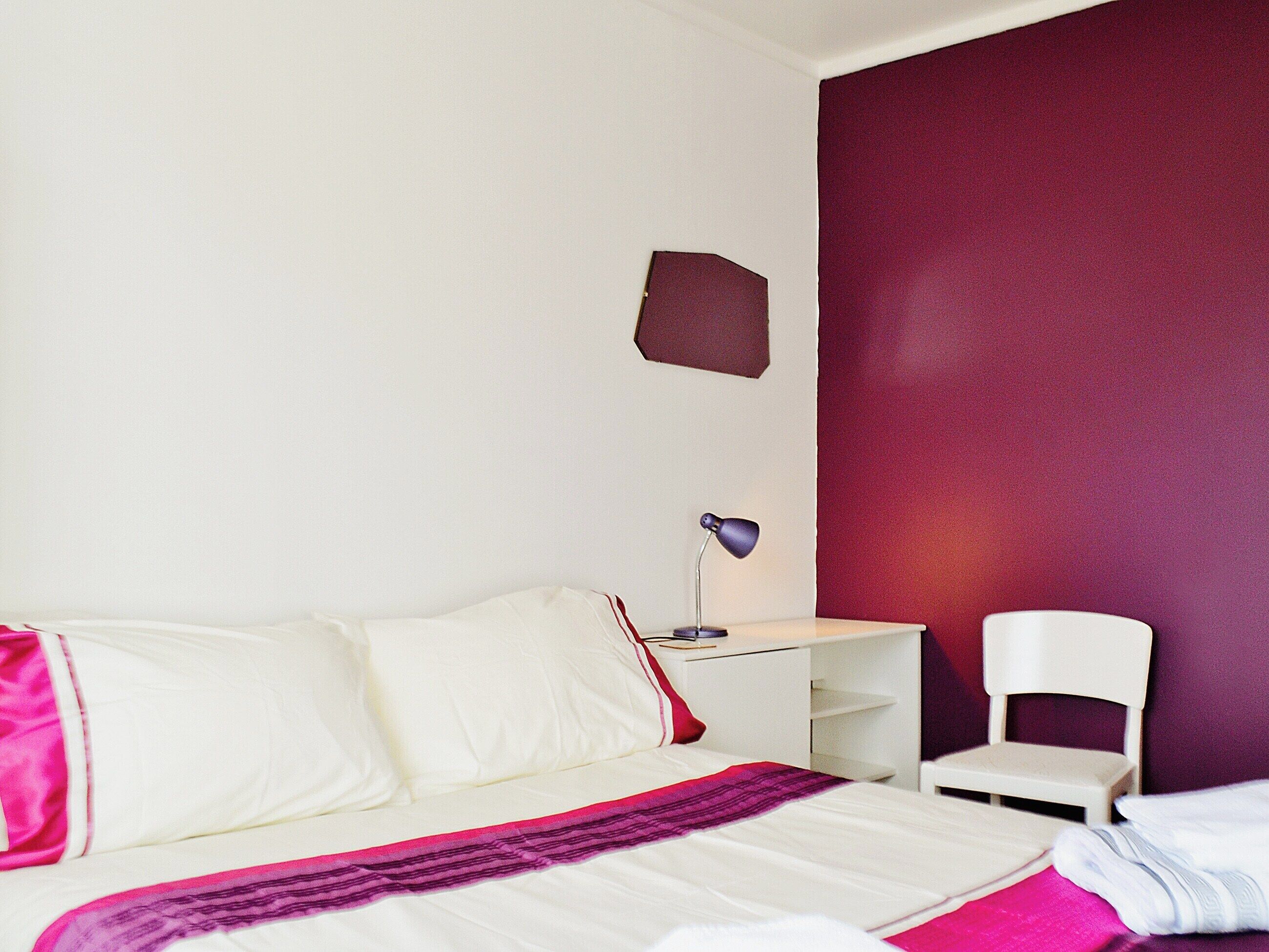 Une chambre d’hôtel avec un lit, un bureau, une chaise et une table de chevet.
