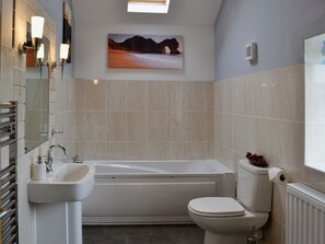 A bathroom with a bathtub, toilet, sink, and a painting on the wall. - 2 bedroom accommodation in Tynlon, near Rhosneigr (Tynlon, near Rhosneigr)