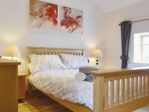 A neatly made bed with a wooden headboard, two bedside tables with lamps, and artwork on the wall. - 2 bedroom accommodation in Tynlon, near Rhosneigr (Tynlon, near Rhosneigr)