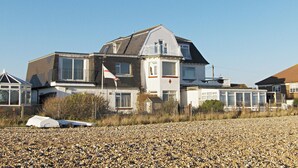 A two-story house with a sloped roof, multiple windows, and a flag on the roof. - 1 bedroom accommodation in Pevensey Bay (Pevensey Bay)