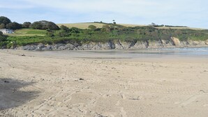 A sandy beach with footprints, a grassy hill, and a building in the background. - 3 bedroom accommodation in Constantine, near Falmouth (Constantine, near Falmouth)