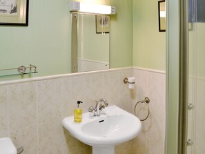 A bathroom with a white sink, a glass shower enclosure, and a mirror.