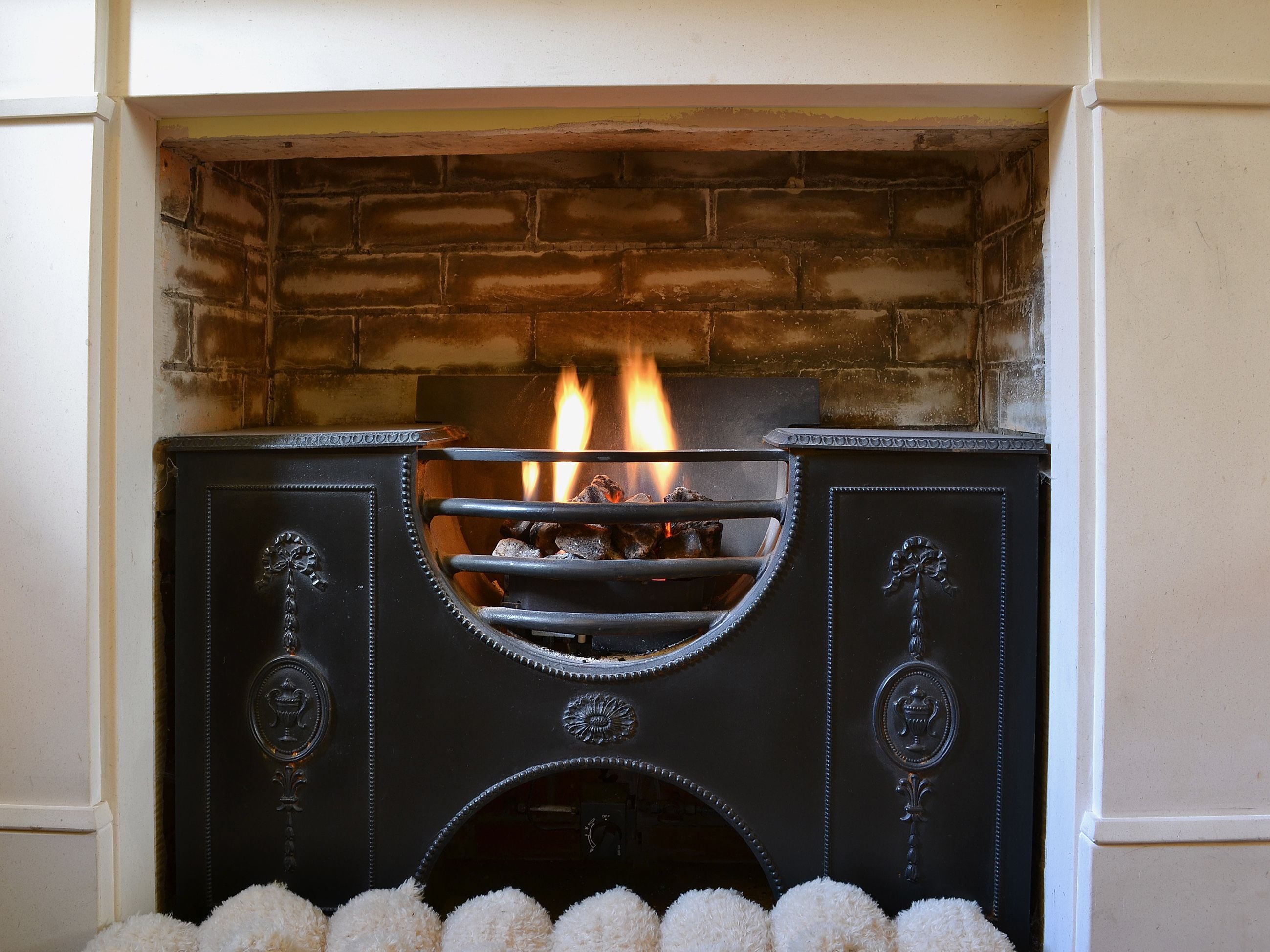 A fireplace with a brick surround, a metal grate, and a decorative emblem.