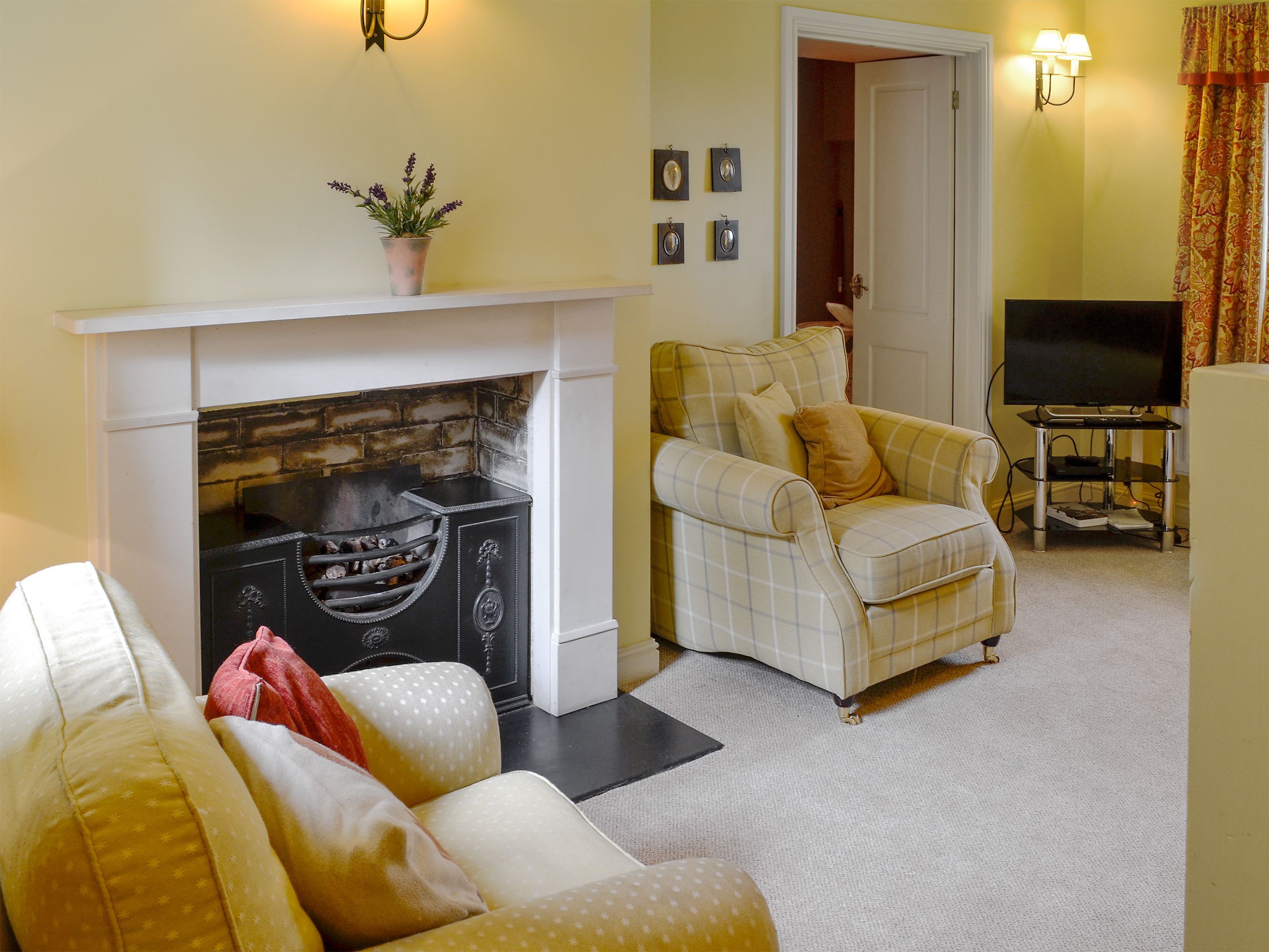 A living room with a fireplace, a sofa, a television, and a door leading to another room.