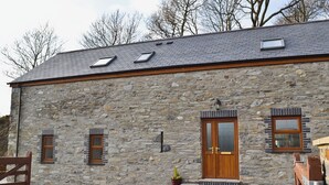 Un bâtiment en pierre avec un toit en pente, deux fenêtres, une porte en bois et un petit porche.
