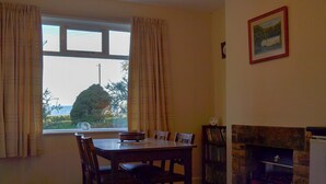 A dining area with a table and chairs, a fireplace, and a bookshelf. - 2 bedroom accommodation in Pentrich, near Ripley (Pentrich, near Ripley)