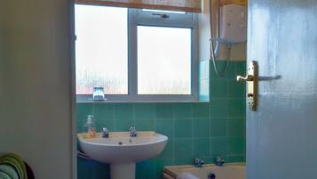 A bathroom with a sink, a window, and a bathtub.