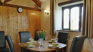 Un comedor con una mesa de madera, seis sillas y un jarrón de flores amarillas.