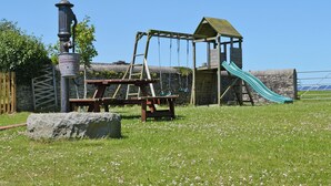 Un parque infantil con columpios, tobogán y una mesa de picnic.