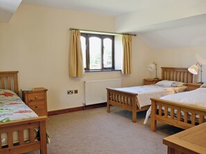 Quarto com duas camas de madeira, uma janela com cortinas, um radiador e luminárias de cabeceira.