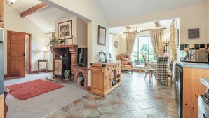 A spacious living area with a fireplace, a dining table, and a kitchen area with a microwave. - 1 bedroom accommodation in Arkleby, near Cockermouth (Arkleby, near Cockermouth)