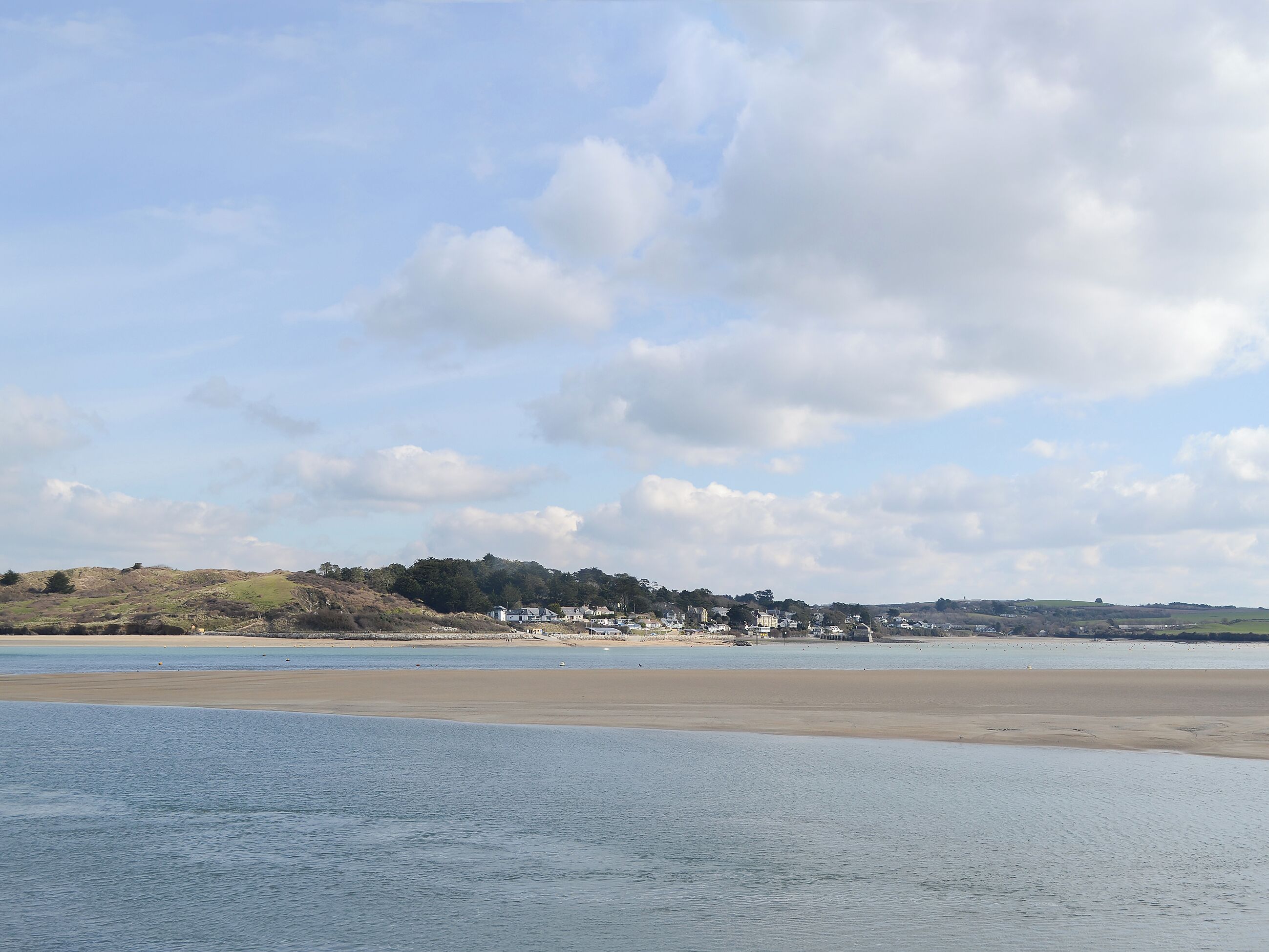 A coastal landscape with a sandy beach and a small settlement in the distance.