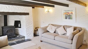Una sala de estar acogedora con un sofá color beige, dos sillones, una chimenea y una obra de arte enmarcada en la pared.