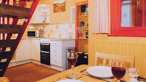 A cozy kitchen with white cabinets, a microwave, and a red-framed window.