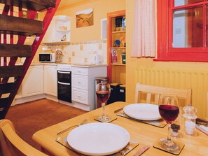 Una cocina acogedora con armarios blancos, un microondas y un ventanal con marco rojo.