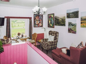 Ein gemütliches Zimmer mit Esstisch, Stühlen, einer Couch und einer rosafarbenen Raumtrennung.