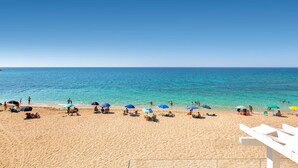 A beach with clear blue water, people relaxing under umbrellas, and a white structure in the foreground. - L'Attico di Alessia by Perle di Puglia (Maruggio)