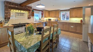 A kitchen with a central island, wooden cabinets, a stove, and a dining area with chairs.