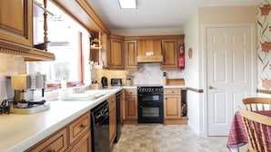 A kitchen with wooden cabinets, a dishwasher, a stove, and a sink.