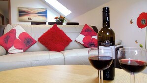 Een kamer met een houten tafel, een fles wijn en twee glazen rode wijn.