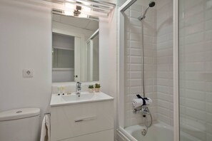 Een moderne badkamer met een wit wastafelmeubel, spiegel en douche.
