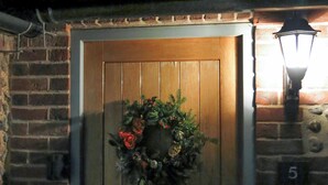 A wooden door with a wreath, a brick wall, and a number '5' on the right. - 3 bedroom accommodation in Wiveton, near Cley next the Sea (Wiveton, near Cley next the Sea)