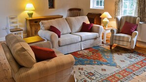 A cozy living room with a sofa, armchair, and a patterned rug. - 3 bedroom accommodation in Wiveton, near Cley next the Sea (Wiveton, near Cley next the Sea)