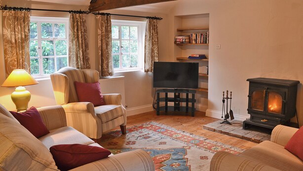 A cozy living room with a fireplace, a television, and a bookshelf. - 3 bedroom accommodation in Wiveton, near Cley next the Sea (Wiveton, near Cley next the Sea)