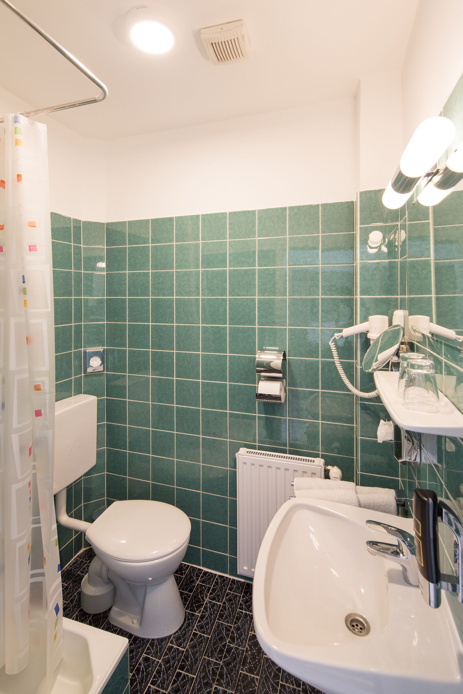 A bathroom with a toilet, sink, and shower area.