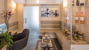 Habitación de hotel moderna con una mesa de centro de vidrio, un sofá, un cuadro en la pared y una vitrina para vinos.