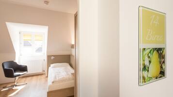 Un dormitorio con cama, una silla, un ventanal y una pared con un letrero.
