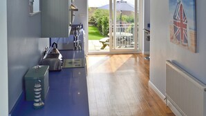 Une cuisine moderne avec un plan de travail bleu, un four encastré et une vue sur un jardin grâce à une porte vitrée.